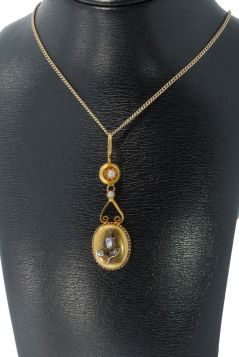 14 karaats gouden antieke ketting hanger met een bloemapplique waarin gezet 3 roosgeslepen diamanten gedecoreerd door 2 zaadparels. Totale afmetingen van dit sieraad zijn 48x14mm, gewicht bijna 3 gram, conditie mooi antieke staat. Gestempeld met het 585 g