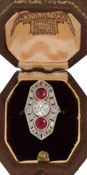 Exclusieve 18 karaats witgouden Art Deco ring met grote solitair oudslijpsel diamant van ca. 0,70ct(5,8mm) SI, geflankeerd door 2 robijnen(totaal ca. 0,60). In platina millegrain zetting omlijst door nog eens 18 stuks achtkant- en oudslijpsel diamanten. V