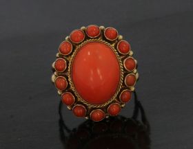 Robuuste 14 karaats geelgouden vintage dames ring met een grote cabochon geslepen dieprode bloedkoraal(15x11mm) omlijst door 14 kleinere bloedkoralen. De ringmaat is 17,25(54), stevige uitvoering van 6 gram, afmetingen ringkop 22x20mm. Goudmerkje uitgesle