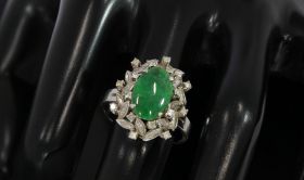 Witgouden klassieke ring met centrale donkergroene Jade(12x8mm) cabochon edelsteen omlijst door 16 briljant geslepen diamanten(totaal ca. 0,30ct) in fraaie zetting. Solide uitvoering van 6 gram, de ringmaat is 19(60), aanpasbaar omdat de onderzijde van de