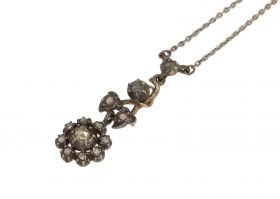 Antieke 14 karaats gouden en zilveren hanger met 13 roosgeslepen diamanten, bloemvormig aan zilveren ankerschakel ketting. Draaglengte van dit sieraad is 43cm, ragfijne schakel van 1mm breed, afmetingen hanger 32x10mm. Conditie mooi antieke staat, tinsold