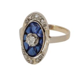 14 karaats antieke geel- en witgouden ring met een centrale diamant van 0,10ct omlijst door 10 roosgeslepen diamantjes en saffieren. Verfijnd gemaakt juweel, de ringmaat is 15(47), afmetingen ringkop 18x11mm, stijl minimalistisch. Conditie mooi antieke st