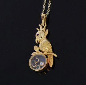 Handgemaakte 18 karaats geelgouden papegaai ketting hanger met robijn oogje en glaasje waarin smaragd robijn saffier en diamant. Afmetingen van dit sieraad inclusief hangoogje zijn 37x15mm, gewicht 4,20 gram. Conditie fraai, gestempeld met het 750 goudmer