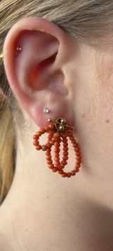 Antiek set 14 karaats gouden oorschroeven(geen gaatjes nodig) met lusvormig bloedkoraal design en kapittel versiering. Draaglengte van dit sieraad is 35mm, gewicht 8 gram. Conditie fraai antiek staat, getoetst als zijnde 14 karaats goud 585/1000 goudgehal
