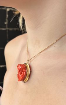 14 karaats geelgouden hanger, tevens te dragen als broche, met een handgestoken bloedkoraal camee portret van een dame, Art Nouveau stijl. Betreft een robuuste uitvoering van ruim 15 gram, afmetingen 35x27mm, totale hoogte 17mm, conditie fraai. Gestempeld