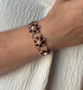 Fraaie 14 karaats gouden dames armband met een entourage van granaten en parels, handgemaakt juweel. Draaglengte van dit sieraad is 17cm, robuuste en solide uitvoering van ruim 30 gram, breedte schakels 20mm. Voorzien van eveneens gouden veiligheidskettin