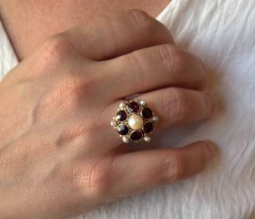 Fraaie 14 karaats gouden dames ring met een entourage van granaten en parels, handgemaakt juweel. De ringmaat is 18,25(57), doorsnee ringkop 20mm, solide uitvoering van 6 gram. Gestempeld met het 585 goudmerk, Hollands gekeurd eikenblaadje, conditie uitmu