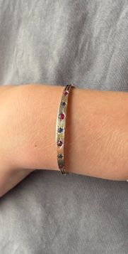 Rosegouden antieke armband uit de Art Deco periode bovenzijde gezet met 4 robijnen en 3 saffieren in stergravure, handgemaakt juweel. Betreft een kleine maat, binnenzijde gemeten ca. 16,5cm(56x50mm), gewicht 6,50 gram. Breedte bovenzijde armband 6mm aflop