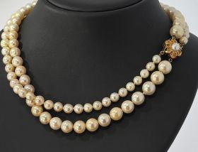 Zoetwaterparel collier aan 14 karaats gouden bloemsluiting(14mm). Draaglengte van dit sieraad is 40cm(hoog in de hals te dragen), parels speels geregen ene snoer oplopend van 5,5mm tot 9mm, andere snoer aflopend van  9mm tot 5,5mm. Conditie fraai, slot ge