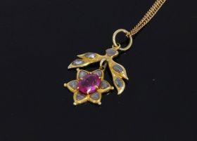 Handgemaakte 14 karaats gouden ketting hanger met bloemapplique waarin een facetgeslepen robijn(7x5mm) omlijst door 11 roosgeslepen diamanten van ca. 2,5/3mm per stuk. Herkomst India, fraai juweel, afmetingen van dit sieraad inclusief hangoogje zijn 30x18