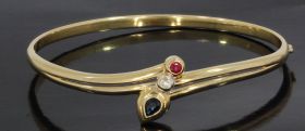 14 karaats geelgouden bangle slavenarmband met saffier, robijn en diamant. Binnen omtrek gemeten is ca. 17,5cm(6,2x5,2cm), breedte kop van de armband met edelstenen is 16mm, aflopend naar 3mm onderzijde, gewicht 9,50 gram. Conditie fraai, gestempeld met h